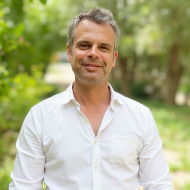 Inhaber Stephan Schillhahn-Schluck Mann in weißem Hemd, lächelnd in einer grünen Parklandschaft.